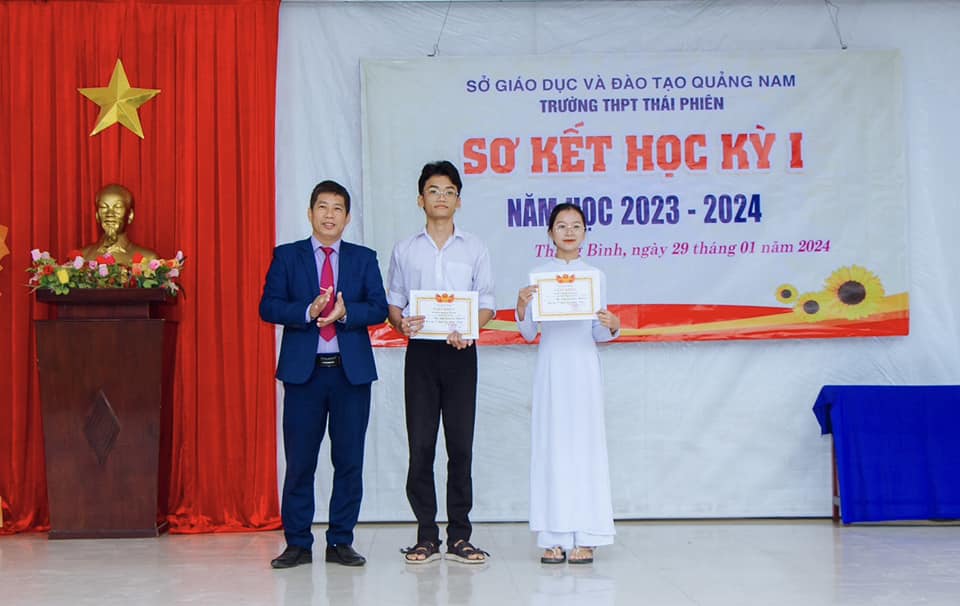 Thầy giáo Đoàn Thanh Liêm trao giấy khen cho 2 học sinh xuất sắc nhất trường trong HKI